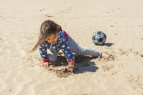 イースターで風の強い日にビーチの砂で遊ぶ女の子 — ストック写真