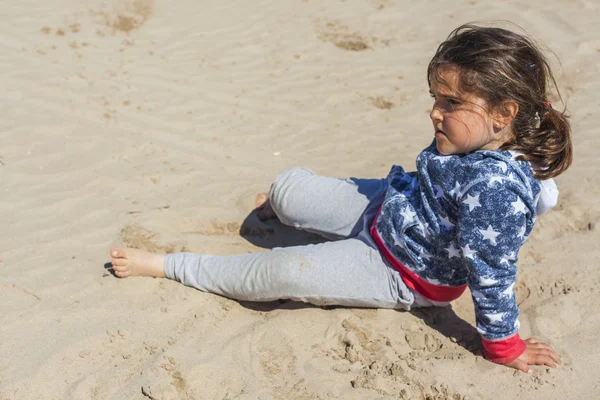 Ragazza in posa nella sabbia della spiaggia in una giornata ventosa a Pasqua. S — Foto Stock