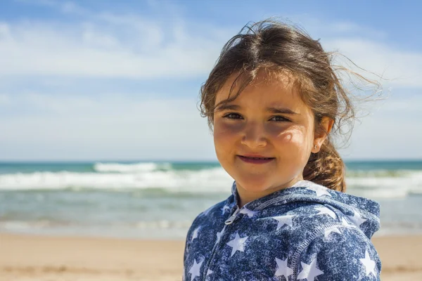 Close up ragazza sorridente in posa in spiaggia in una giornata ventosa a Pasqua — Foto Stock