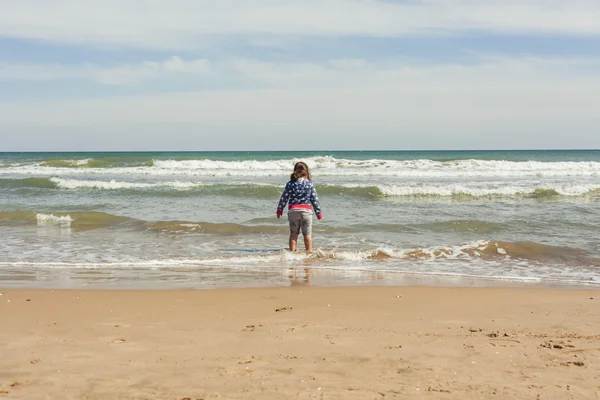 Retrovisore full shot ragazza a piedi verso la riva della spiaggia in un — Foto Stock