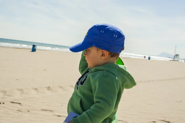 Lado-maneira médio tiro menino com um chapéu azul andando na bea — Fotografia de Stock