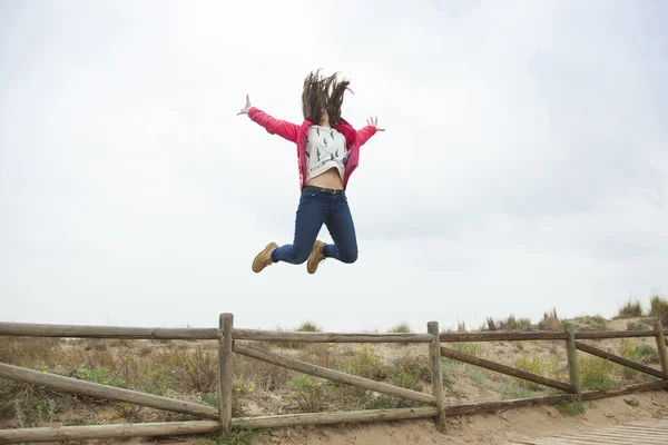 Full shot adolescente feliz saltando con las manos extendidas cerca de th — Foto de Stock