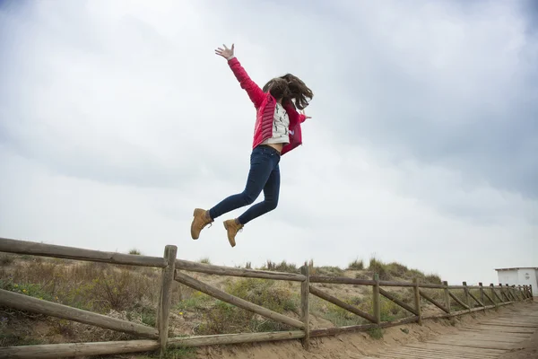 Full shot adolescente feliz saltando con las manos extendidas cerca de th — Foto de Stock