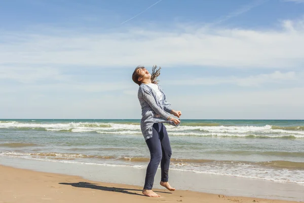 Full shot de un adolescente sonriente saltando en la orilla del mar de la bea — Foto de Stock