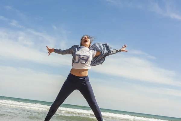 Sonriente adolescente saltando en la orilla del mar de la playa en una d clara — Foto de Stock