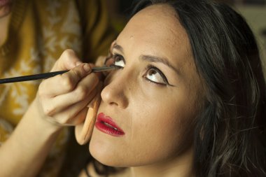 Make-up artist applying cosmetics to a model in a set
