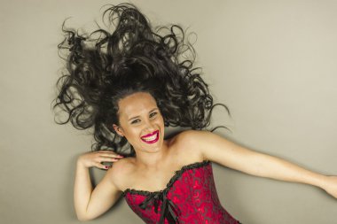 Gülen güzel kadın uzun saçlı ve Kızıl korse ile uzan