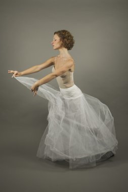 Young expressive ballerina with a white long tutu practicing bal