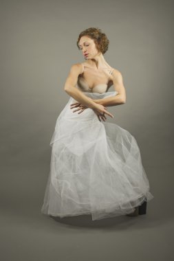 Young expressive ballerina with a white long tutu practicing bal