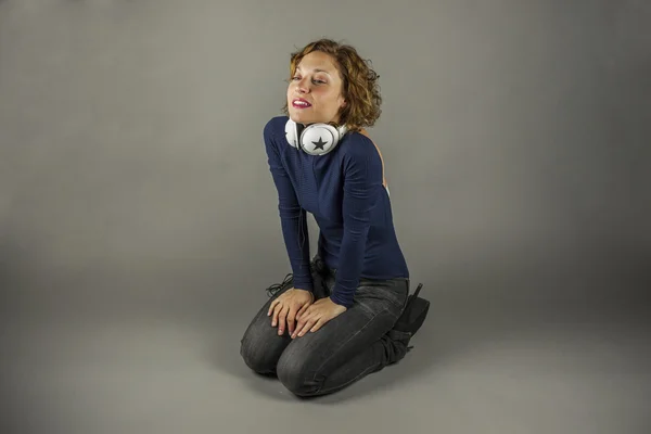 Retrato de mujer joven con auriculares en cuclillas en el suelo — Foto de Stock