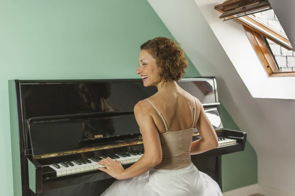 Bailarina vista trasera tocando y tocando el piano en una casa — Foto de Stock