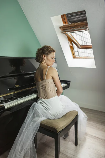 Bailarina vista trasera tocando y tocando el piano en una casa — Foto de Stock