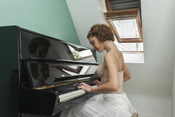 Ballerina utför och spela piano i ett hus — Stockfoto