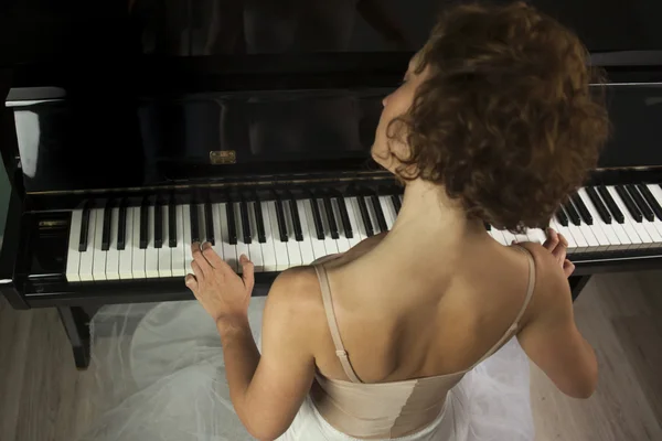 Bailarina vista trasera tocando y tocando el piano en una casa — Foto de Stock