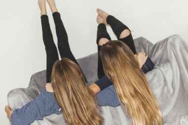 İki kız baş aşağı bacaklar ile gri bir kanepe döşeme