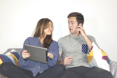 Genç çift portresi oturup bir kanepe cihazlar ile
