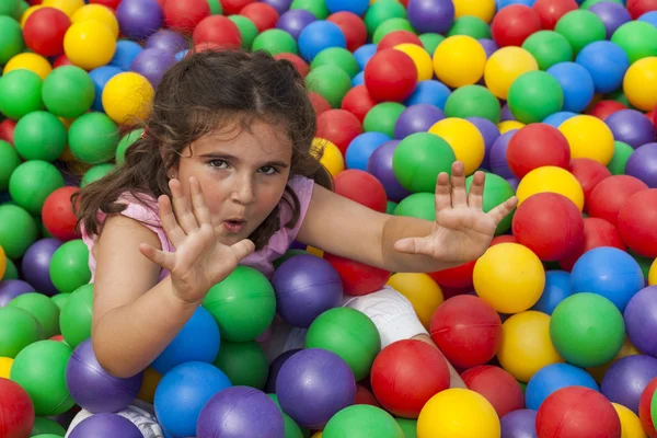 Menina se divertindo jogando em uma piscina de bola de plástico colorido — Fotografia de Stock