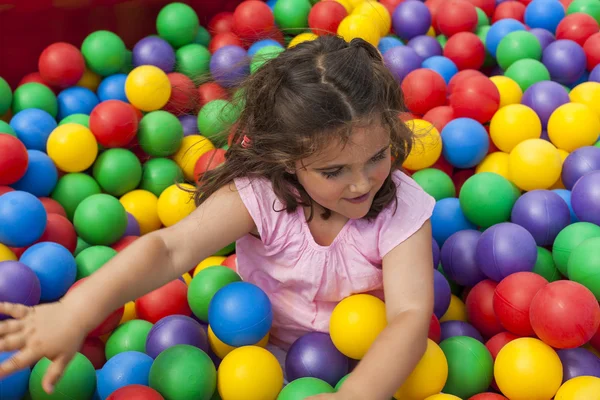 Menina se divertindo jogando em uma piscina de bola de plástico colorido — Fotografia de Stock