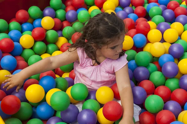 Menina se divertindo jogando em uma piscina de bola de plástico colorido — Fotografia de Stock