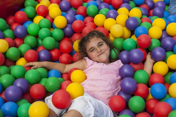 Menina deitar-se em uma piscina de plástico colorido bola — Fotografia de Stock