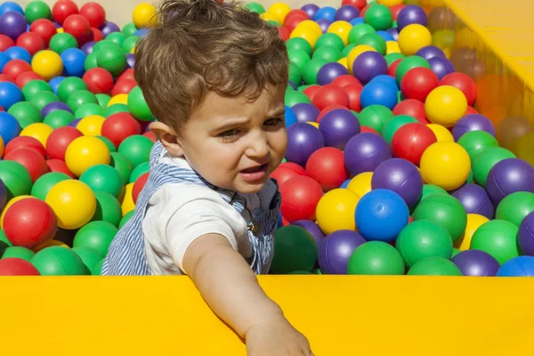 Bebé niño divirtiéndose jugando en una piscina de bolas de plástico colorido — Foto de Stock