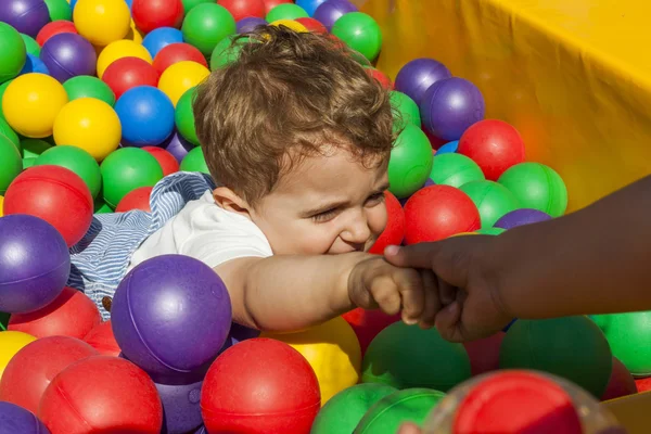 Flickan att hjälpa hennes lillebror att få ut ett bollhav — Stockfoto