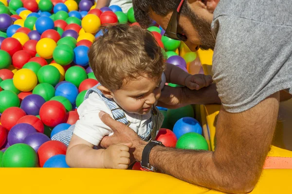 Papai ajudando bebê menino saindo de uma piscina de bolas de plástico colorido — Fotografia de Stock