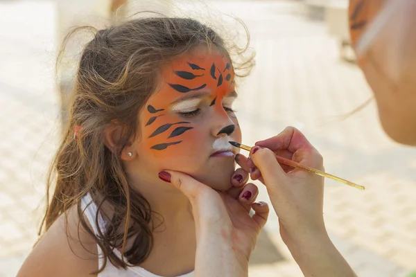 Mädchen bekommt ihr Gesicht von Malerin geschminkt. — Stockfoto