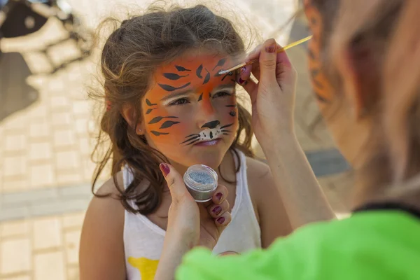 Girl getting her face painted by painting artist. — Stock Photo, Image