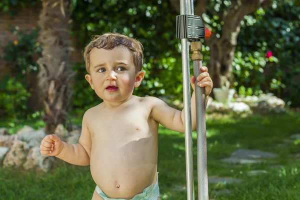 Menino brincando com água no jardim . — Fotografia de Stock