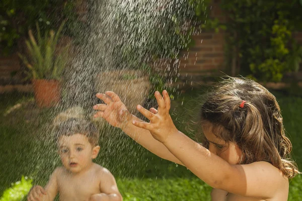 Ragazza un bambino ragazzo ritratto giocare con acqua in giardino . — Foto Stock