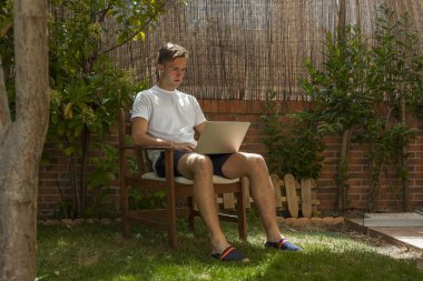 Bir bilgisayar ile ahşap bir sandalyede oturup genç adam portresi