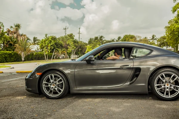 Long shot d'un jeune homme conduisant une Porsche Cayman. Scène urbaine . — Photo