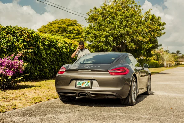 Plan long d'un jeune homme au téléphone, debout près d'une Porsche Cay — Photo