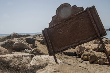 B kıyıya yakın kayalarda bulunan bir tabela arkası