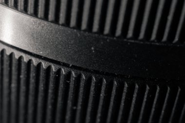 Siyah makro soyut doku arka planında endüstriyel eğimli ince paralel oyuklar var. Yumuşak bir bant, bokeh ve dokunsal derinliği ima eden yumuşak odak ile geliştirilmiş kopyalama alanı sunar.