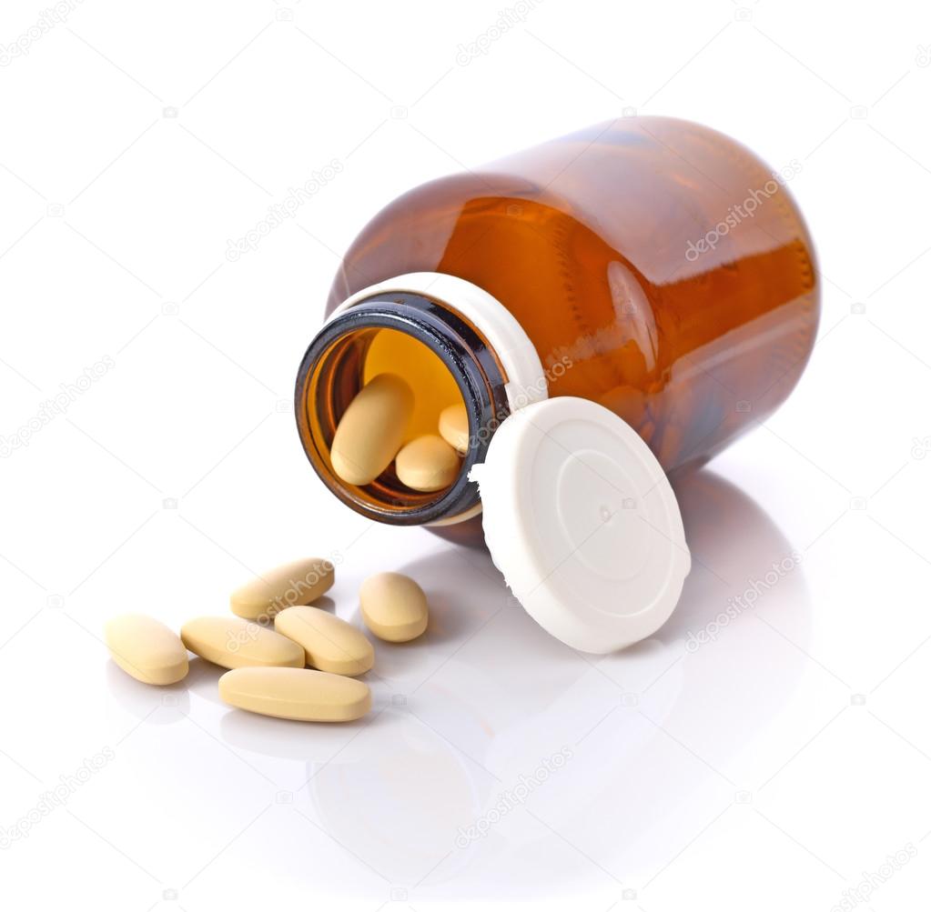 Pill bottle spilling pills on to surface isolated on a white bac