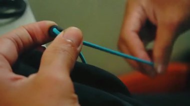 Giysi fabrikasındaki profesyonel bir terzinin siyah kapüşonlu ceketine bağlama işlemi.