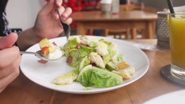 Restoranda Sezar Salatası yiyen bir kadın. Kıtır marul, yumurta, tütsülenmiş biftek, çıtır çıtır ekmek, parmesan peyniri ve hafif Sezar sosuyla servis edilir.