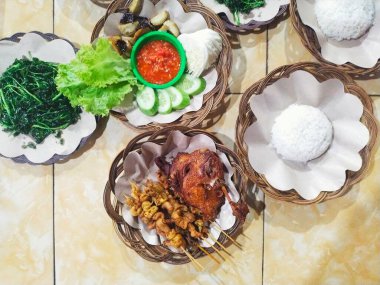 Kızarmış ördek ve tavuk derisi satay taze sebzeler, dilimlenmiş salatalık, kızarmış su teresi, acı sos ve beyaz pirinç ile servis edilir. Hepsi bir Sundan restoranında rattan tabaklarda servis ediliyor.