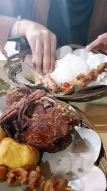 Geleneksel bir Endonezya restoranında tavuk derisi satay, ciğer ve taşlık satay, kızarmış tofu, sambal ve kızarmış ördek yemek.