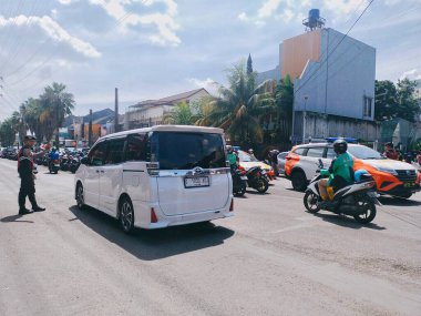 Bandung, Endonezya - 25 Aralık 2025; bir polis memuru araba ve motosiklet trafiğini düzenliyor
