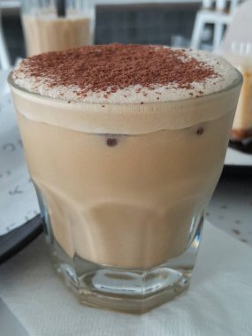 Kahve dükkanında bir bardak soğuk buzlu kapuçino ve çikolata taneleri.