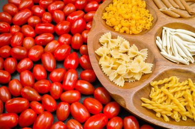 Ahşap kase makarna çeşitli karışımı, küçük kırmızı domates closeup