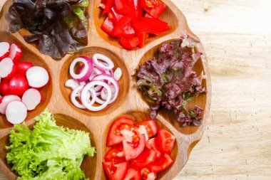 Wooden bowl with mixed ingredients for fresh vegetable salad