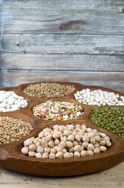 Wooden bowl of various legumes on wooden background copy space