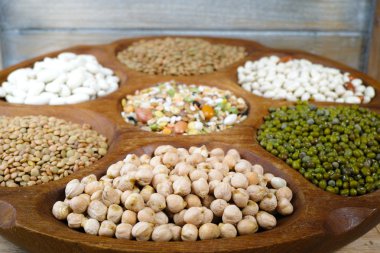Wooden bowl of various legumes on wooden background copy space