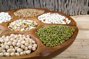 Wooden bowl of various legumes on wooden background copy space