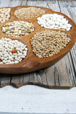 Wooden bowl of various legumes on wooden background copy space