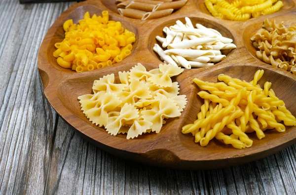 Ahşap kase makarna ve küçük kırmızı domates çeşitli karışımı 